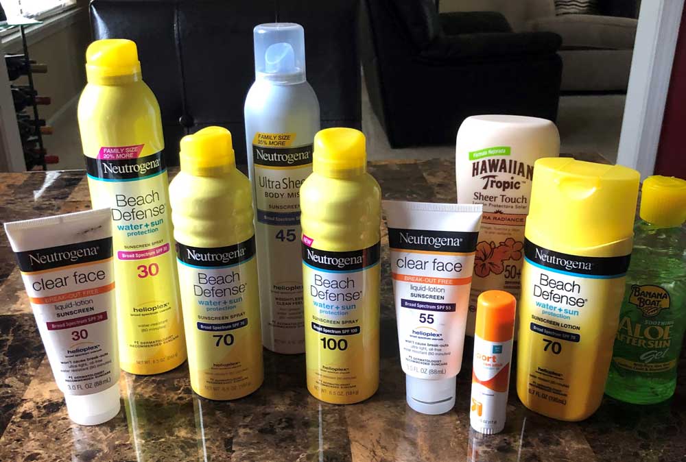 Many different bottles of sunscreen lined up on a counter