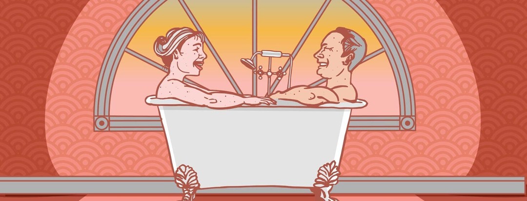 a couple sit in a tub laughing
