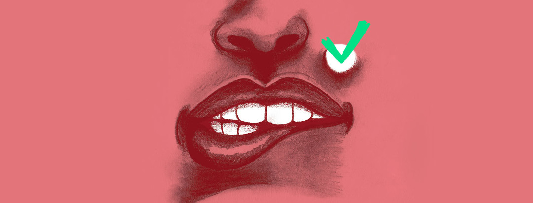 close up of teeth biting a lower lip and a green check mark on a white spot on the upper lip