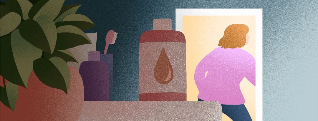 A bottle of spray tan sits unused in a dark bathroom as a woman walks away.
